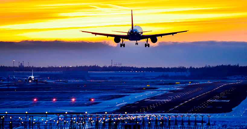 The airplane landing at the airport runway at sunset