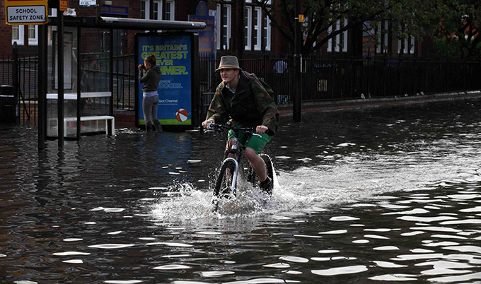 man on a bike cycling through a flood