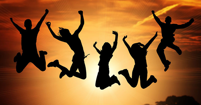 Children jumping in the air in front of sunrise.