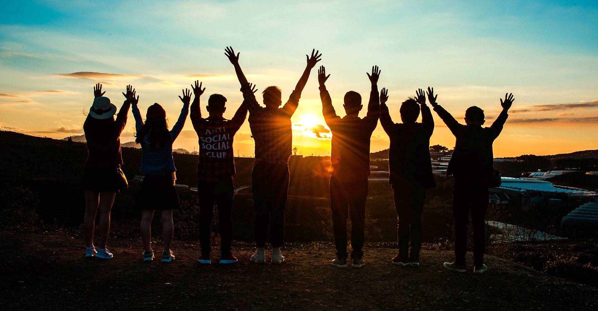 Emerging Minds: Teenagers with their hands in the air, at sunset.