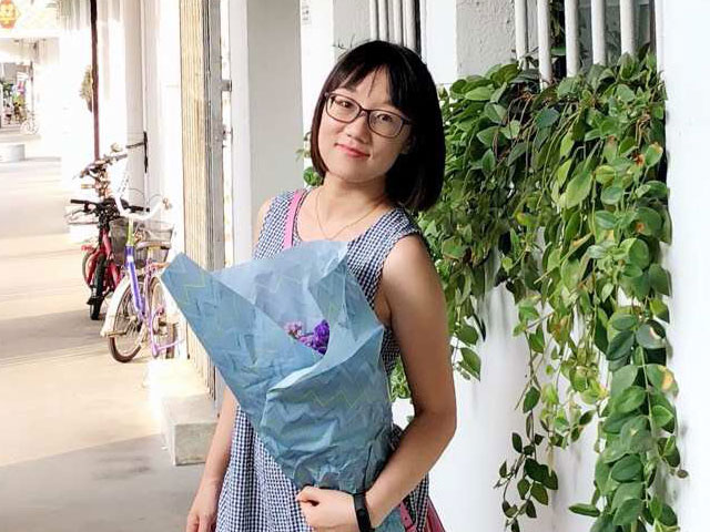 Photograph of Ji Xi holding flowers on the Singapore campus.