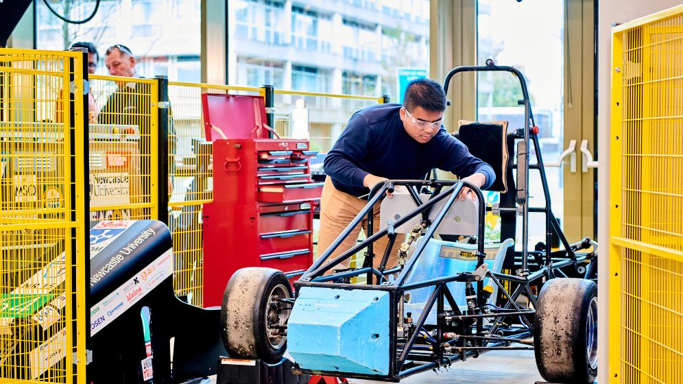 A student is working on the chassis of Newcastle's Formula Student race car.