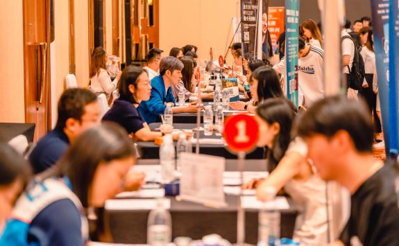 Row of consultation tables at an alumni event in China, attended by a diverse group of individuals engaging in discussions.