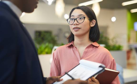 A Business School student on an internship speaking to a colleague holding a clipboard