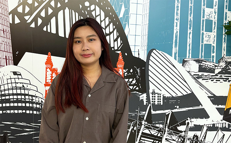 NUBS student Ella Kong standing in front of a mural depicting various North East landmarks	