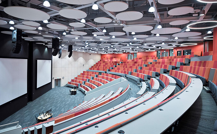 Large, modern lecture theatre in the Frederick Douglass Centre, with tiered seating and circular ceiling panels.