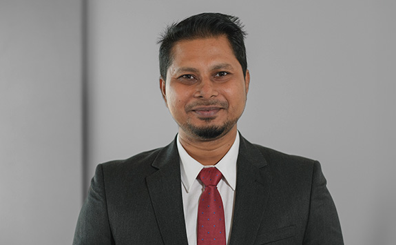 Headshot of Iftekhar Ahmed wearing a dark suit, white shirt and red tie.