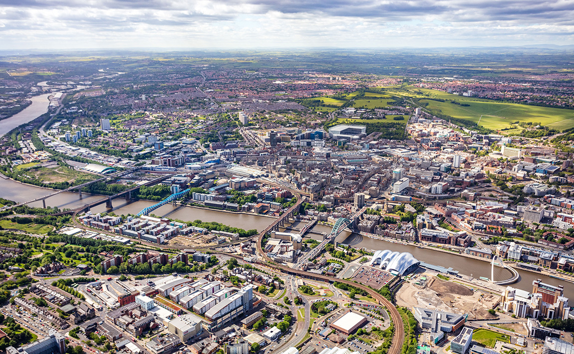 Aerial view of Newcastle University campus and the surrounding city, showcasing modern architecture and green spaces