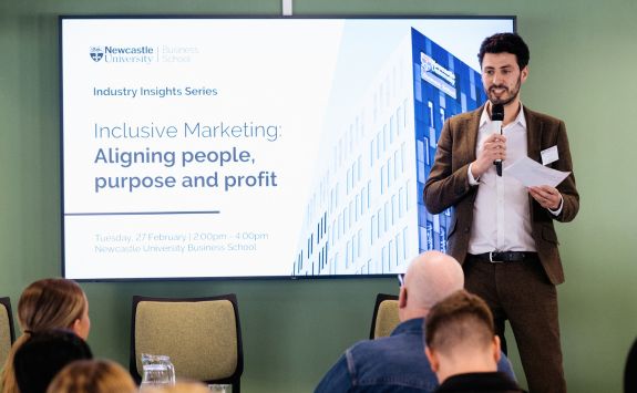 Steven Sadi (Business Partnerships Manager) introduces a session at an industry insights event. He is holding a microphone and standing in front of a screen displaying the title "Inclusive Marketing: Aligning people, purpose and profit: