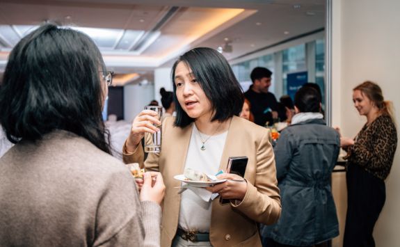 A networking moment at the British Council scholarships launch event, with two women engaged in conversation. One woman is holding a plate and a drink.