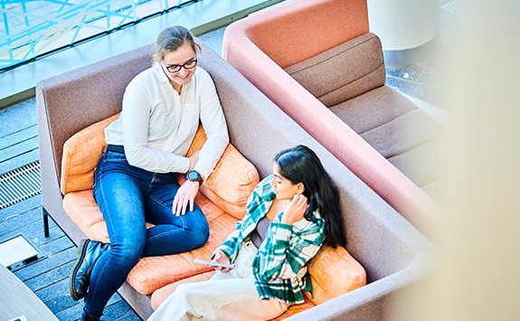 Two students sitting together on a couch in the Urban Sciences Building.