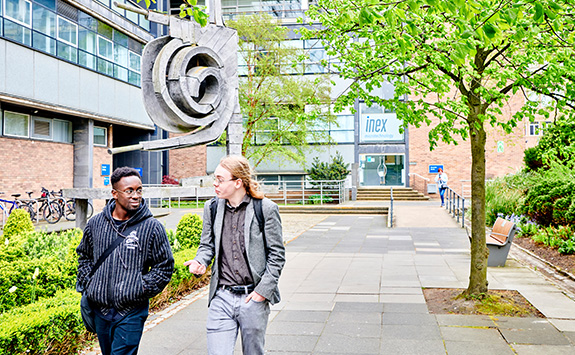 Two students walking outside the Herschel building on Newcastle University campus.