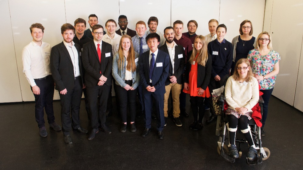 A group of students standing in front of a white wall.